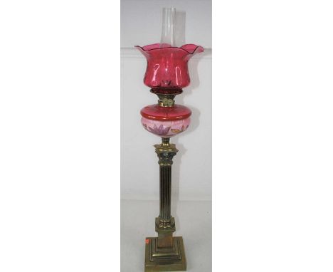 A Victorian pedestal oil lamp, having a cranberry tinted etched glass shade above a pink glass font with floral decoration, r