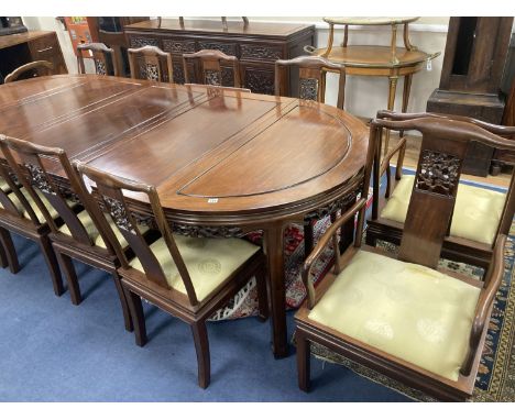 A 20th century Chinese carved hardwood dining room suite comprising sideboard fitted with four drawers above four carved pane