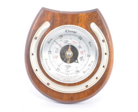 A 20th Century wall hanging silver faced barometer in the form of a horseshoe upon a wooden mahogany plaque. Measuring approx