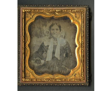 Daguerreotype photograph depicting a portrait of a woman. She is dressed in a black dress with black lace fingerless gloves, 