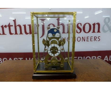 A brass fusee skeleton clock, with enamelled moonphase dial, cased