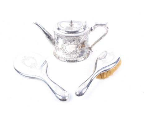 A silver backed mirror and a brush and silver-plated oval teapot. This embossed and engraved with cartouches and leaf bands, 