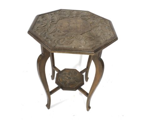 An Arts and Crafts style stained wood side table. With octagonal top and lower pot shelf, both deeply carved with tulips and 