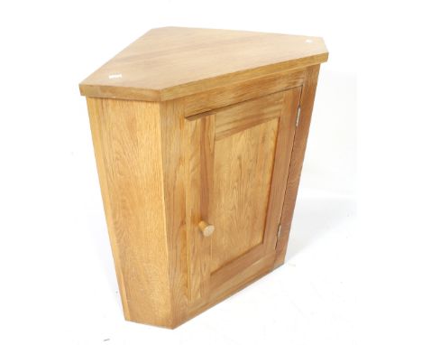 A contemporary oak corner cupboard. With single panelled door. L71cm x D44cm x H78cm