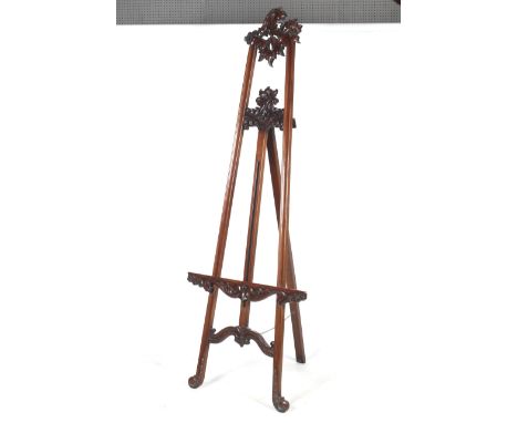 A large contemporary mahogany easel. Scroll feet to a adjustable picture shelf,carved flower motif to a scroll top. H218cm x 