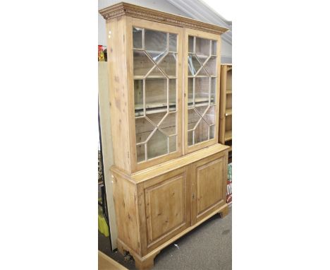 A 20th century pine dresser bookcase. Having astral glazed two door upper bookcase section with dentil cornice mouldings, abo