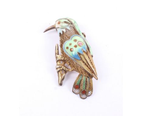 A filigree silver-gilt and polychrome enamel brooch in the form of an exotic bird on a branch. Stamped 'Silver', 5.5g gross