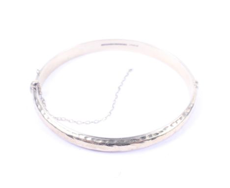 A vintage 9ct gold part foliate engraved hollow D-section hinged bangle. Convention hallmarks, 8g