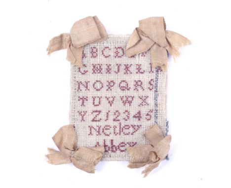 A 19th century miniature sampler. Possibly once part of a needle case or pin card, the alphanumeric sampler stitched in red t