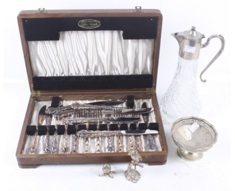 An assortment of silver plate and metalware. Including a canteen of flatware, a silver plated claret jug, paperweights and mo