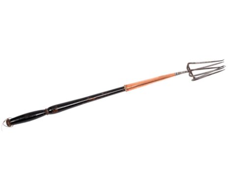 A George III steel six-prong fork, with copper ferrule and turned, ebonised wood handle, 69cm l  Wear and old rust pitting, t