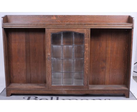‘Liberty &amp; co’ An Arts and Crafts oak bookcaseCentral glazed door flanked by open shelves, 183cm wide; 119cm highOld mark