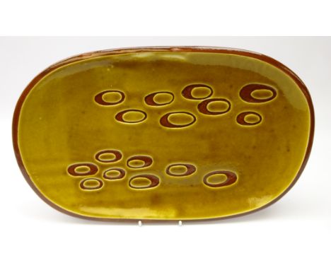 1960's/ 70's slipware dish of rounded rectangular form with incised circular decoration, inscribed to underside 'K McF 11-75'