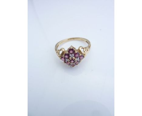 A gem-set ring, set with pink stones, possibly tourmaline, and four single-cut diamonds, with scrolling shoulders, in 9ct gol