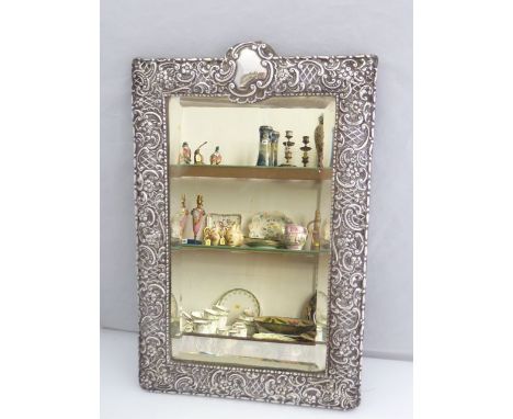 A late Victorian silver hanging mirror, probably Cohen & Charles, Birmingham, 1900, the rectangular frame mounted with flower