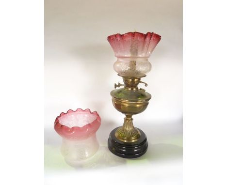 An oil lamp with embossed brass base upon an ebonised weighted foot (converted to electricity), accommodating a good quality 