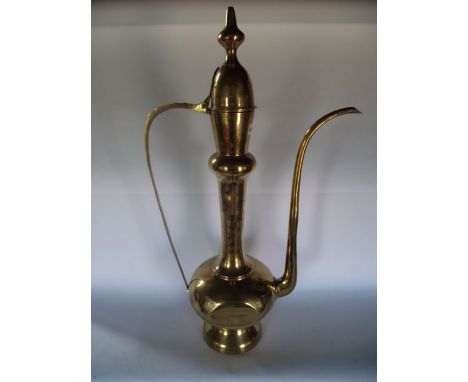 A substantial eastern brass ewer, possibly Turkish, with a hinged finial lid, elongated spout and applied handle, 81 cm tall 