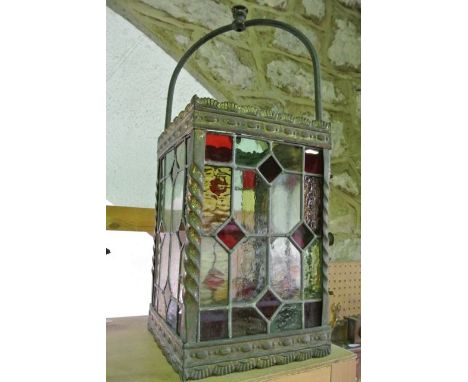 A vintage brass framed ceiling hanging four sided lantern of rectangular form enclosing leaded glass panels in shades of pale