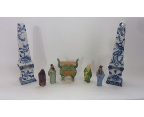 A pair of ceramic obelisks with blue and white chinoiserie style floral decoration raised on four ball supports and plinths o