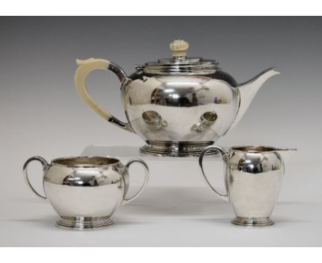 George V silver Art Deco design three piece tea set, each piece of circular form and standing on a stepped foot, the teapot w