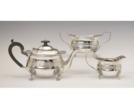 George V silver three piece tea set, each piece having a central reeded band and standing on four scroll feet, makers Robert 