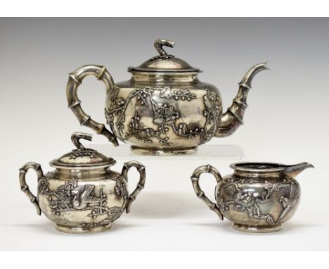 Late 19th/early 20th Century Chinese export silver three piece tea set, each piece decorated in relief with birds amongst pru