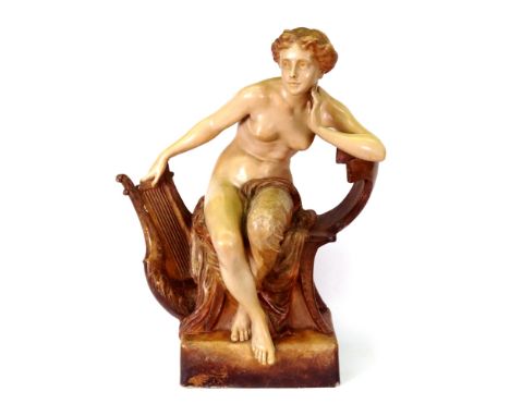 A Goldscheider figure of a young woman, partially draped, seated on a chair, one hand resting on a lyre, on a rectangular bas