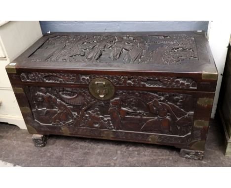 A Chinese carved camphorwood coffer, first half 20th century, brass bound and with side carrying handles, the hinged cover an