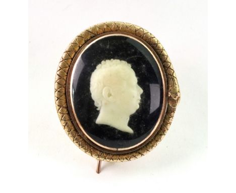 A gold and ivory cameo brooch, early 19th century, with bust in profile facing right on a blue enamel ground, within an Ourob