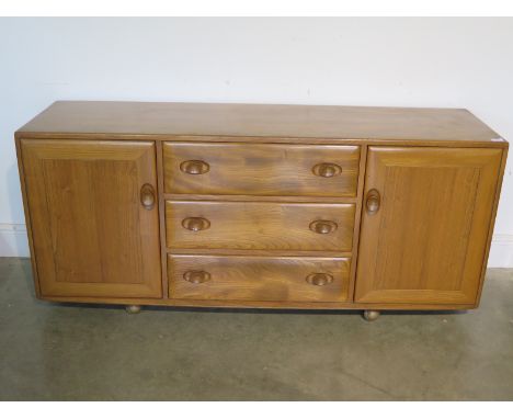 A light elm Ercol sideboard with two doors and three drawers - 68cm tall x 156cm x 44cm deep generally good condition some mi