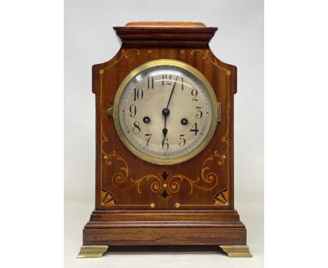 A mantel clock, the silvered dial fitted an eight day movement, striking on a chime, in an inlaid mahogany case, 18 cm high 