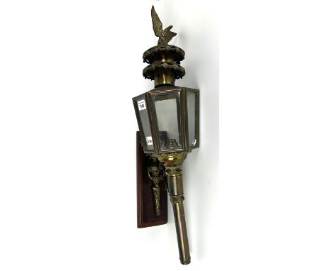A brass and glass coaching type lamp, mounted on a panel 