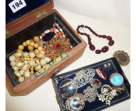 Assorted jewellery and enamel badges in an old box, including cherry amber bakelite beads, scrap silver, etc.