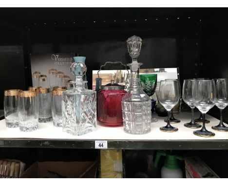 A shelf of drinking glasses, decanters, cranberry glass biscuit barrel etc.,