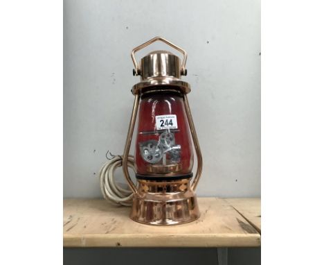 An unusual table lamp in the shape of a hurricane lamp with inset traction engine.