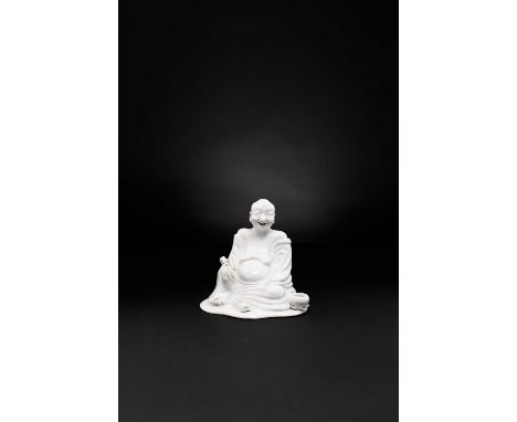 A CHINESE WHITE-GLAZED FIGURE OF A SEATED LUOHAN 18TH CENTURY  Modelled wearing loose monk’s robes, holding a fly whisk in hi
