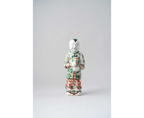 NO RESERVEA CHINESE WUCAI FIGURE OF A BOY KANGXI 1662-1722  Standing on a plinth, holding a vase in his hands, wearing a magu