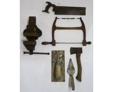 A Woden bench vice, with a small collection of vintage tools, including a fret saw, a tenon saw, a hatchet etc. Condition Rep