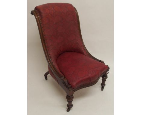 A Victorian mahogany framed slipper chair with floral foliate embossed upholstery on turned supports terminating in ceramic c