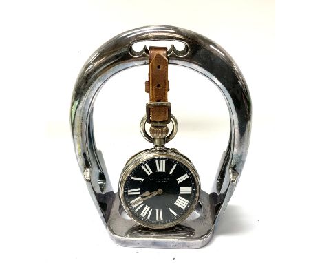 A large Goliath pocket watch with black enamel dial 62mm together with a silver plated watch stand in the form of a stirrup. 