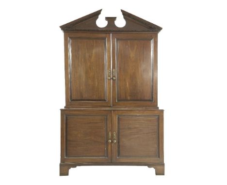 A George III mahogany estate cupboard,with a bold architectural cornice over two panelled doors, enclosing adjustable shelves