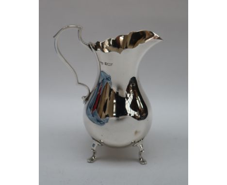 An Edward VII silver cream jug of baluster form with a scrolling handle on four feet, Sheffield, 1903, Mappin and Webb, 16cm 