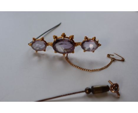 An amethyst brooch set with three oval faceted amethysts to a yellow metal setting, 6cm long, approximately 11.5 grams togeth