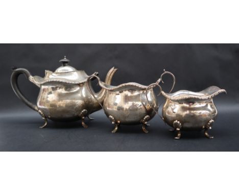 A George V silver three piece tea service with a gadrooned edge and bulbous body on four feet, Birmingham, 1920, S Blanckense