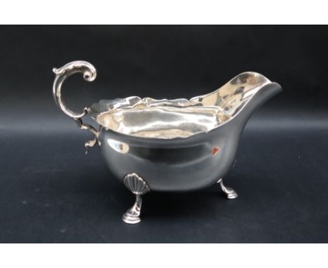 A Victorian silver sauce boat with a flared rim and scrolling handle on three shell capped legs and pad feet, London, 1886, C