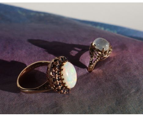 A 9ct gold sapphire and opal dress ring, set with a central cabochon opal surrounded by round brilliant faceted sapphires to 