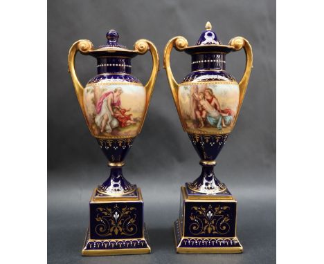 A pair of Vienna style twin handled vases and covers, with a royal blue ground painted with figures playing musical instrumen