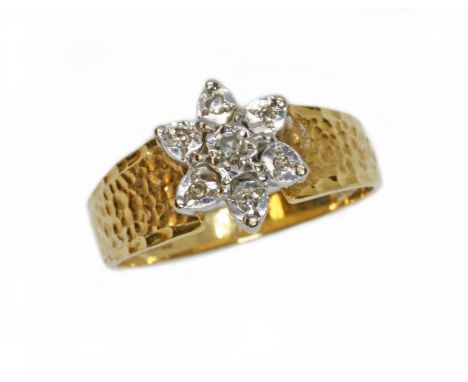 A hallmarked 18ct gold diamond cluster ring, the flower head cluster measuring approximately 10mm in diameter, textured shoul