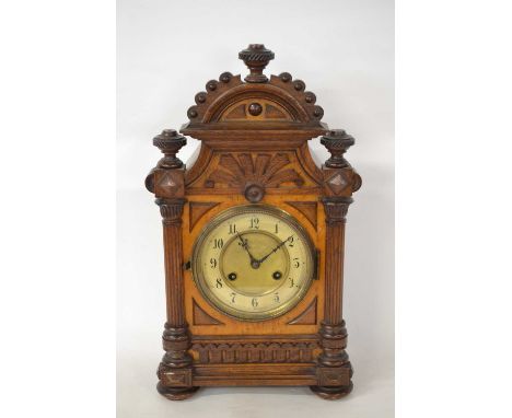 A late 19th Century German mantel clock set in a carved wooden architectural case and fitted with a brass movement, 45cm high