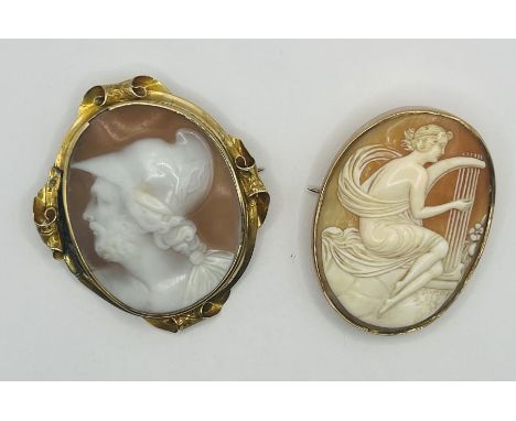 Two shell cameo brooches. One a Victorian yellow metal brooch, with ornate scroll work and featuring a left facing profile of
